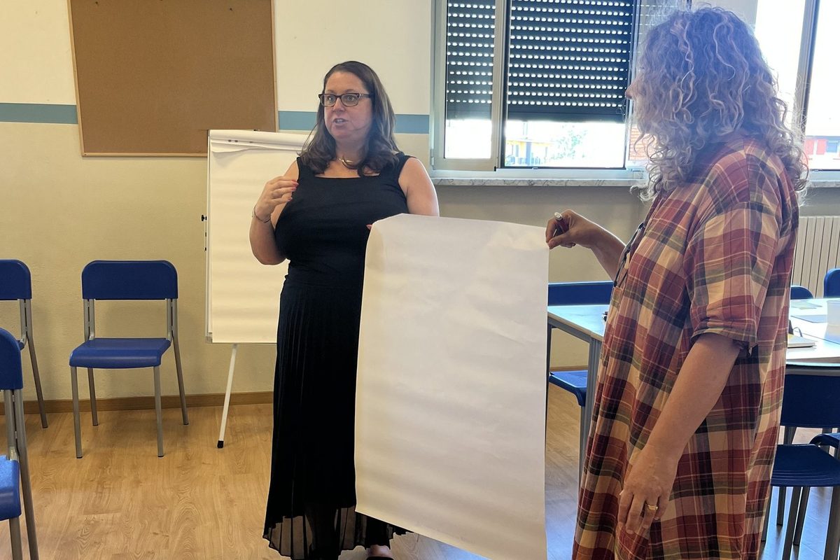 Two colleagues at Andersen International School, Milan, talking an idea through over a large blank sheet