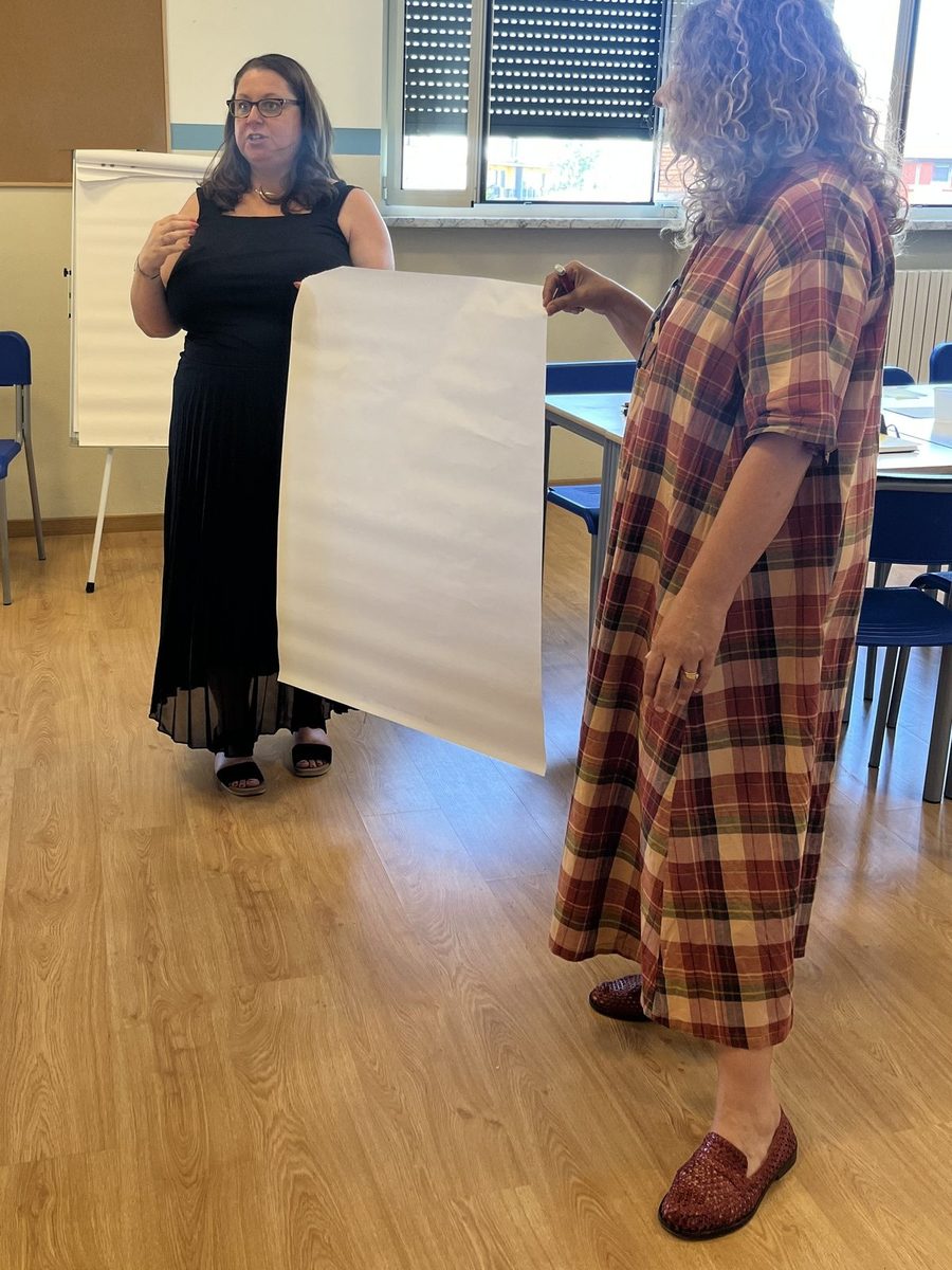Two colleagues at Andersen International School, Milan, talking an idea through over a large blank sheet